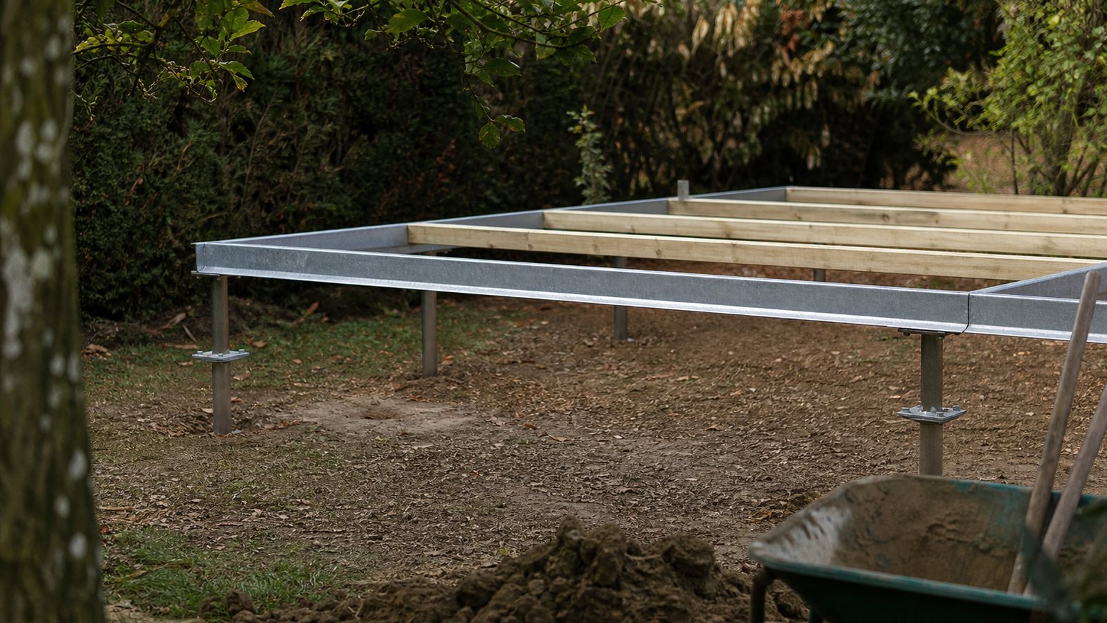 Pieux vissés et plots de fondation installés dans un jardin avant la pose d'un studio