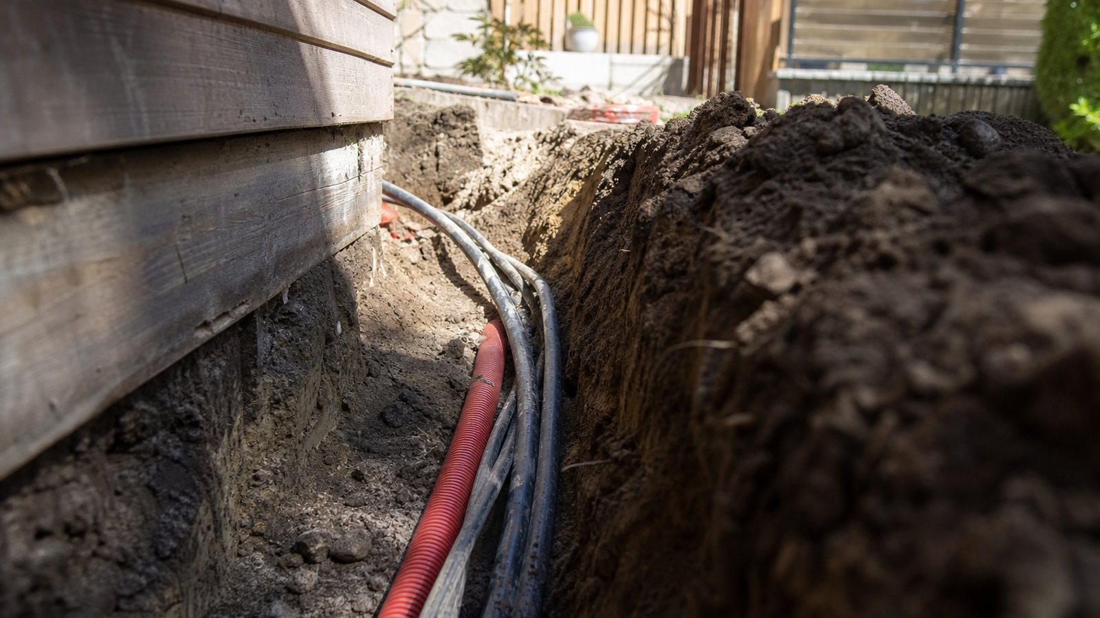 Tranchée ouverte dans une pelouse pour amener électricité et eau jusqu'à un studio de jardin